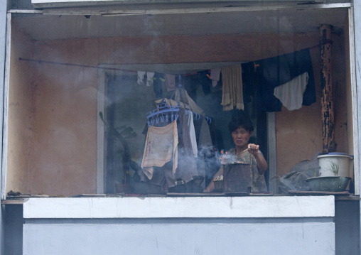 North Korean woman cooking a bbq on her balcony, Pyongan Province, Pyongyang, North Korea