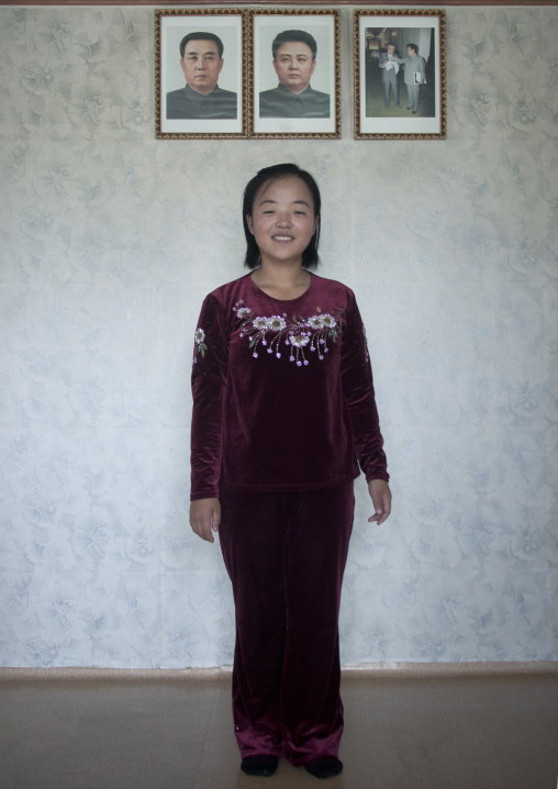 North Korean woman posing below the official portraits of the Dear Leaders in her home, South Hamgyong Province, Hamhung, North Korea