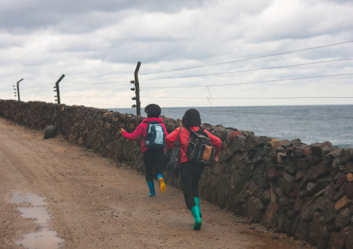 North Korean children running on a muddy road along a fence, North Hamgyong Province, Jung Pyong Ri, North Korea