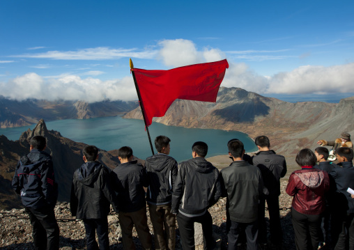 Group of students with red flag in front of lake at mount Paektu, Ryanggang Province, Mount Paektu, North Korea