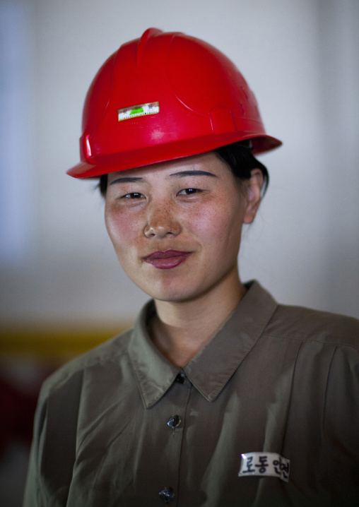 North Korean worker woman wearing a red helmet in a factory, South Pyongan Province, Nampo, North Korea