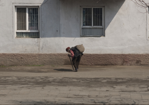 Old and poor woman stooping in the street, South Pyongan Province, Nampo, North Korea