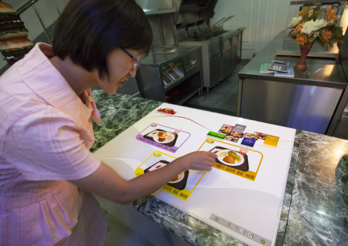 Young North Korean woman looking at menu in a fast food restaurant at Kaeson youth park, Pyongan Province, Pyongyang, North Korea