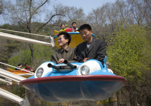 North Korean people having fun on a flying saucer attraction in Taesongsan funfair, Pyongan Province, Pyongyang, North Korea