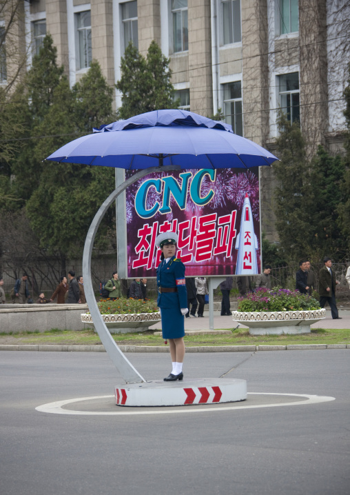 North Korean traffic security officer in blue uniform in front of a propaganda billboard, Pyongan Province, Pyongyang, North Korea