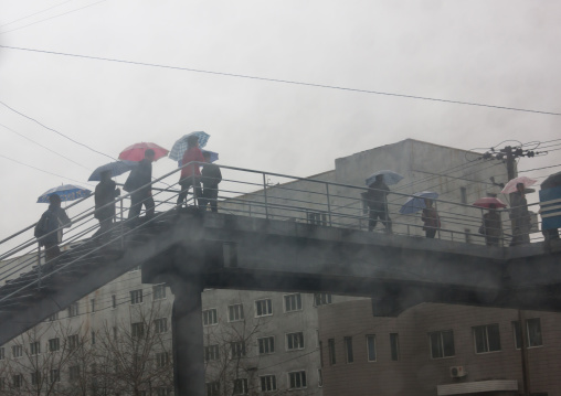 North Korean pedestrians crossing a bridge under the rain, Pyongan Province, Pyongyang, North Korea