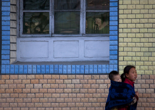 North Korean pioneer girl carrying her brother on her back, Kangwon Province, Wonsan, North Korea