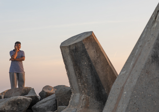 Man speaking on a mobile phone on a jetty, Dhofar Governorate, Mirbat, Oman