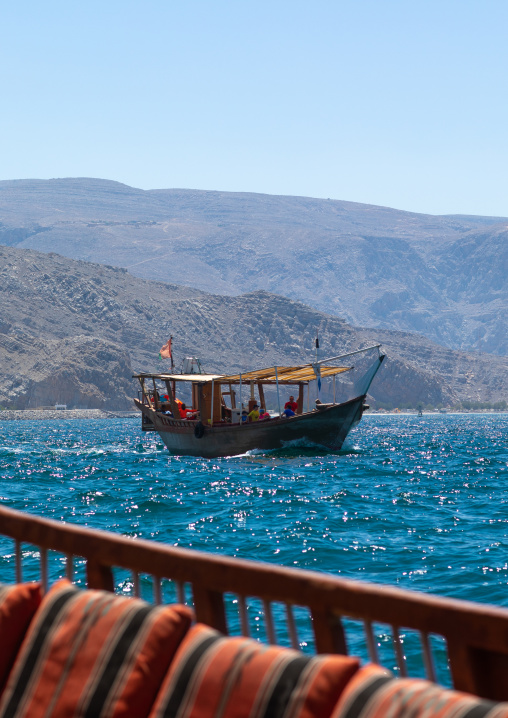 Dhow sailing in the fjords in front of mountains, Musandam Governorate, Khasab, Oman