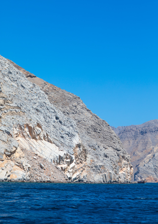 Dhow sailing in the fjords in front of mountains, Musandam Governorate, Khasab, Oman