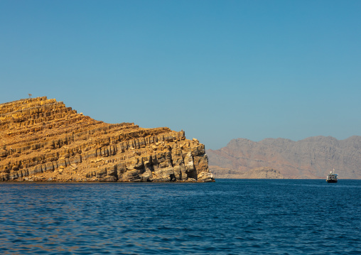 Dhow sailing in the fjords in front of mountains, Musandam Governorate, Khasab, Oman