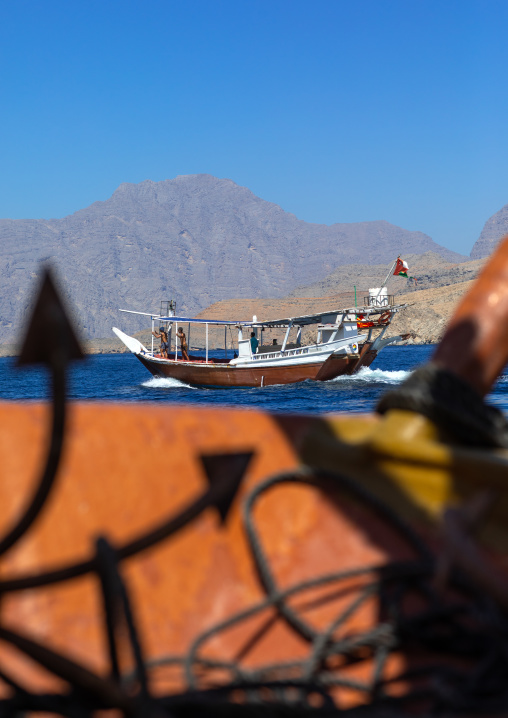 Dhow sailing in the fjords in front of mountains, Musandam Governorate, Khasab, Oman