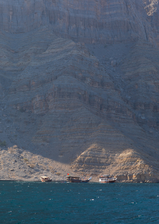 Dhow sailing in the fjords in front of mountains, Musandam Governorate, Khasab, Oman