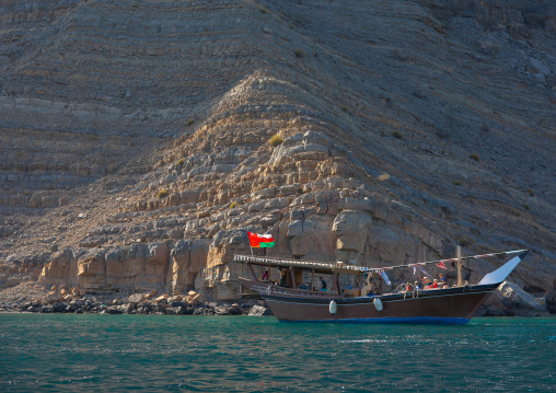 Dhow sailing in the fjords in front of mountains, Musandam Governorate, Khasab, Oman