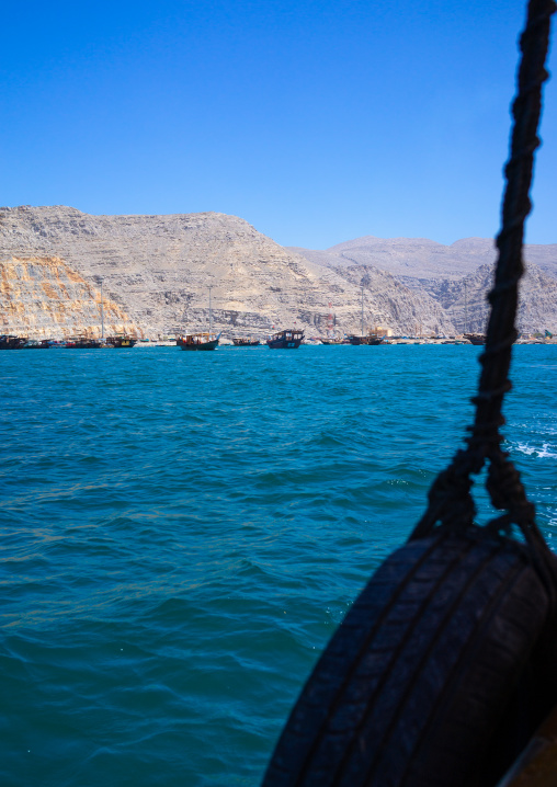 Dhow sailing in the fjords in front of mountains, Musandam Governorate, Khasab, Oman