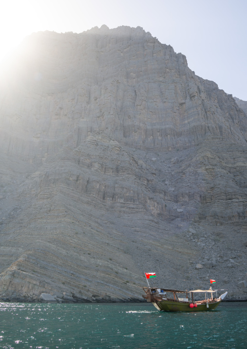 Dhow sailing in the fjords in front of mountains, Musandam Governorate, Khasab, Oman