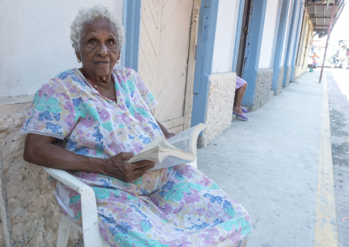 Panama, Province Of Panama, Panama City, Old Panamean Woman Reading In Front Of Her House In The Street In Casco Viejo