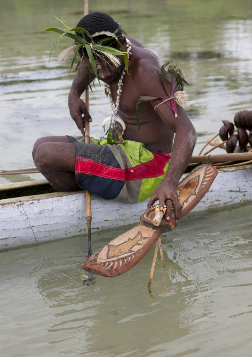 Man on a pirogue making a shark calling, New Ireland Province, Kavieng, Papua New Guinea