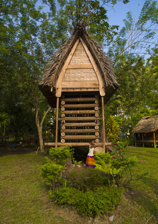 Girl in front of a yam house in a village, Milne Bay Province, Trobriand Island, Papua New Guinea