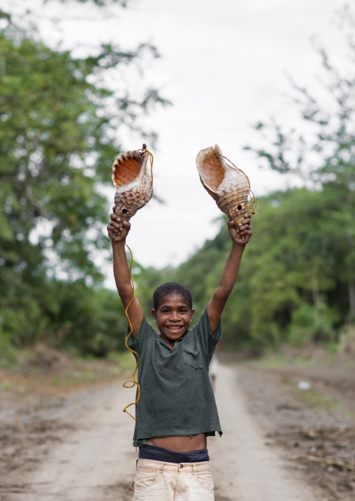 Boy holding two giant shells used to call friends, Milne Bay Province, Alotau, Papua New Guinea