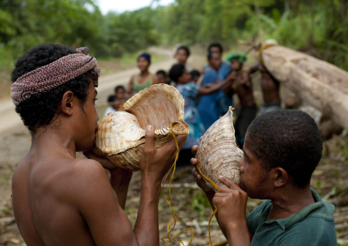 Boys blowing in shells to call friends, Milne Bay Province, Alotau, Papua New Guinea