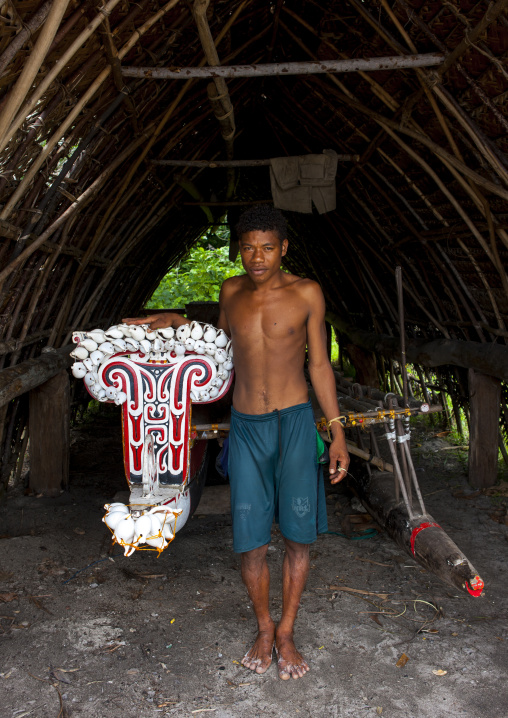 Man in front of kula canoe decorated with shells, Milne Bay Province, Trobriand Island, Papua New Guinea