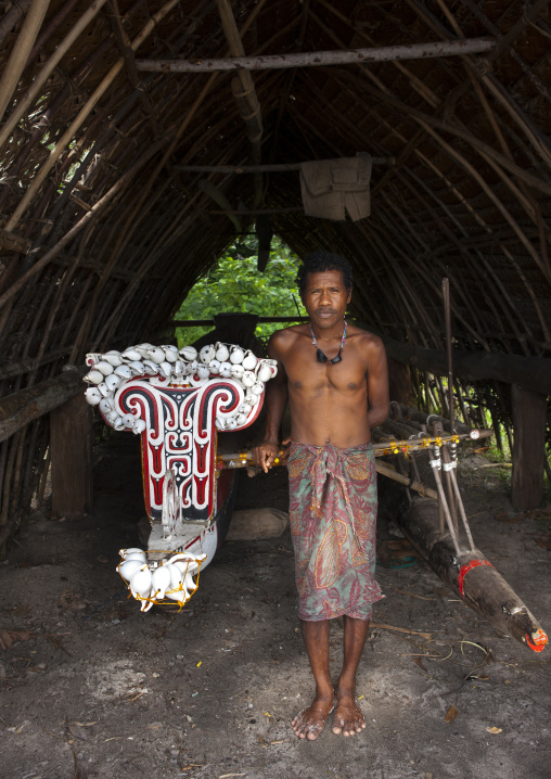 Man in front of kula canoe decorated with shells, Milne Bay Province, Trobriand Island, Papua New Guinea