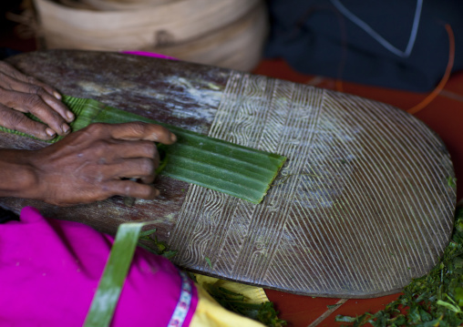 Girl making Doba traditional money with banana leaves on a wooden board, Milne Bay Province, Trobriand Island, Papua New Guinea