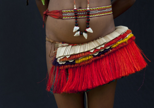 Woman wearing a traditional red skirt made with pandanus and banana leaves, Milne Bay Province, Trobriand Island, Papua New Guinea