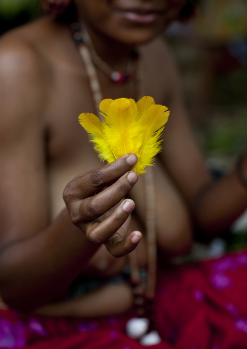 Woman showing a yellow feather used for ceremonies, Milne Bay Province, Trobriand Island, Papua New Guinea