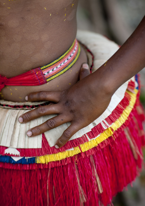 Woman wearing a traditional red skirt made with pandanus and banana leaves, Milne Bay Province, Trobriand Island, Papua New Guinea