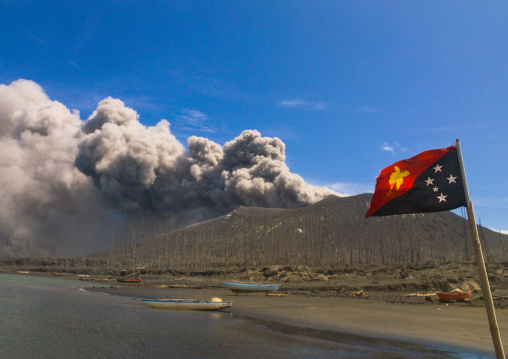 Papuan flag in front of Tavurvur volcano in eruption, East New Britain Province, Rabaul, Papua New Guinea