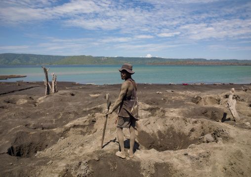 Man digging to find megapode birds eggs in Tavurvur volcano ashes, East New Britain Province, Rabaul, Papua New Guinea