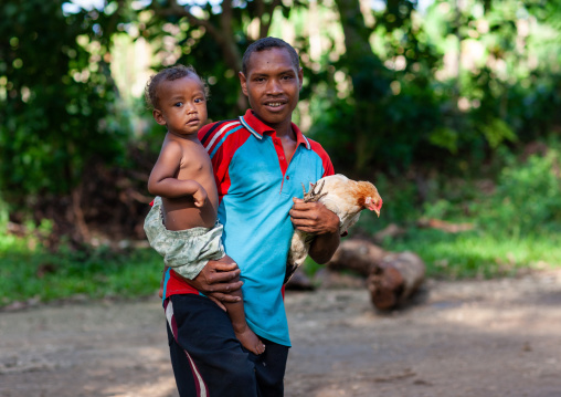 Man carrying his son and a chicken, Milne Bay Province, Trobriand Island, Papua New Guinea