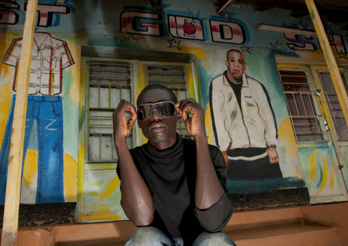 Rwandan man in front of a tailor shop mural, Kigali Province, Kigali, Rwanda