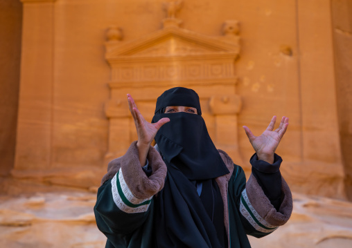 Saudi female guide in front of a tomb in al-Hijr archaeological site in Madain Saleh, Al Madinah Province, Alula, Saudi Arabia