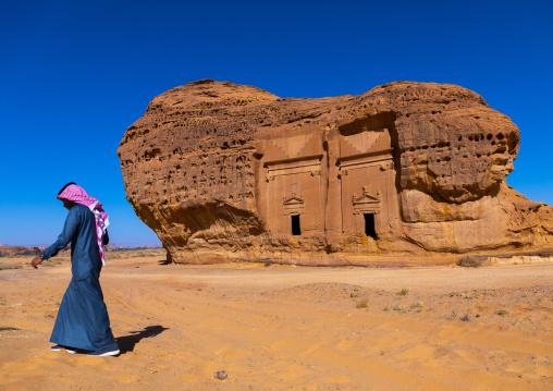 Saudi man walking in front of tombs in al-Hijr archaeological site in Madain Saleh, Al Madinah Province, Alula, Saudi Arabia