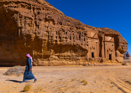 Saudi man walking in front of tombs in al-Hijr archaeological site in Madain Saleh, Al Madinah Province, Alula, Saudi Arabia