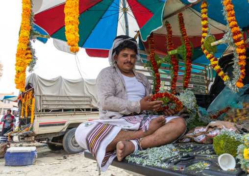 A flower vendor preparing floral garlands and crowns on a market in the back of his car, Jizan Province, Addayer, Saudi Arabia