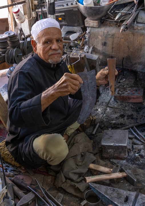 A saudi man prepares a traditional janbiya dagger for sale inside his shop, Najran Province, Najran, Saudi Arabia