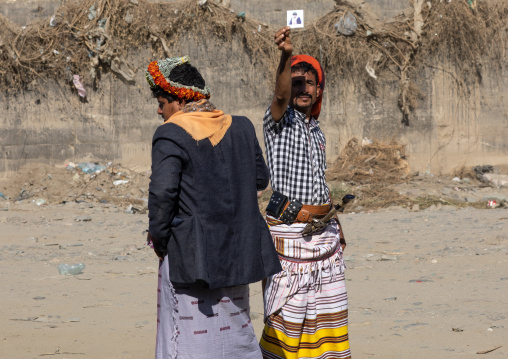 Portrait of flower men wearing floral crowns on the heads and putting a polaroid in the sun, Jizan Province, Addayer, Saudi Arabia