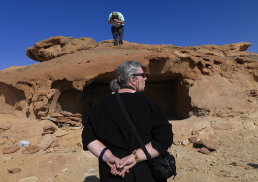 Western tourists in front of a Nabatean tomb in qadeer sand stone castle, Al-Jawf Province, Sakaka, Saudi Arabia