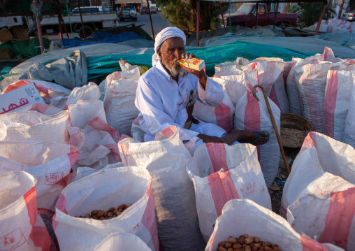 Saudi man drinking juice while selling dates in the market, Najran Province, Najran, Saudi Arabia