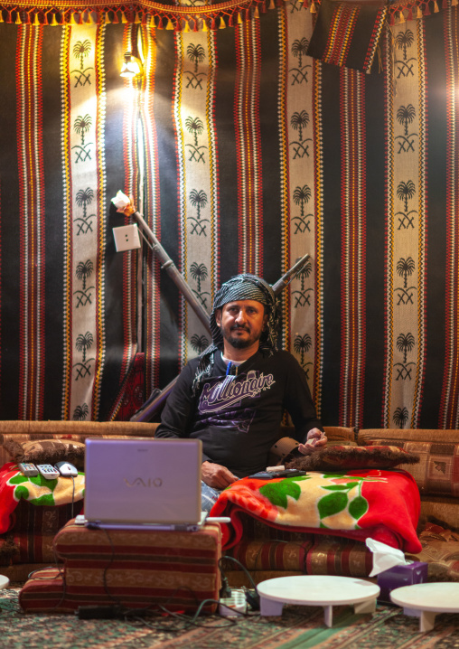 Saudi man using his computer inside his tent, Al-Sarawat, Fifa Mountains, Saudi Arabia