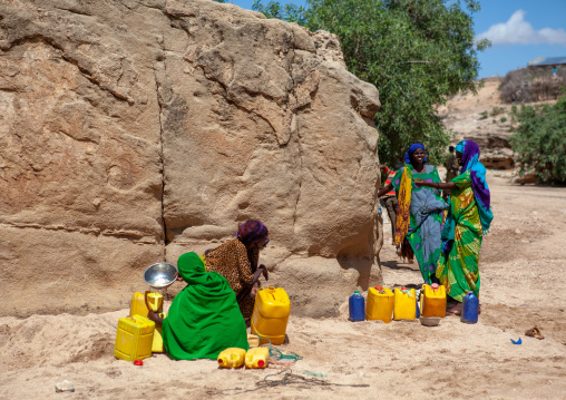 Somali women taking drinking water from a well hole in the sand and pouring it into plastic containers, North-Western province, Lasadacwo Village, Somaliland