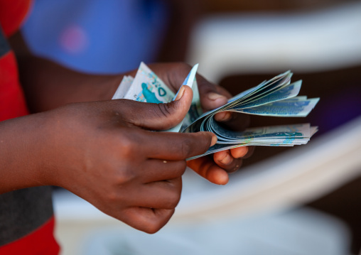 A man is counting schillings notes, Awdal region, Zeila, Somaliland