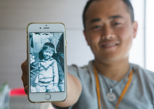 North korean defector joseph park in yovel cafe showing a picture of himself taken in north korea, National capital area, Seoul, South korea