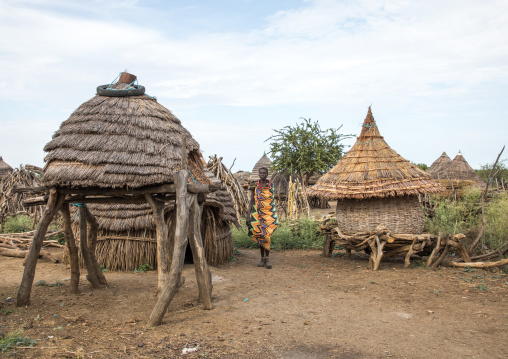 Toposa tribe woman passing near granaries in a village, Namorunyang State, Kapoeta, South Sudan