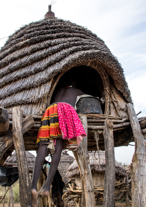 Toposa tribe girl climbing in a granary in a village, Namorunyang State, Kapoeta, South Sudan