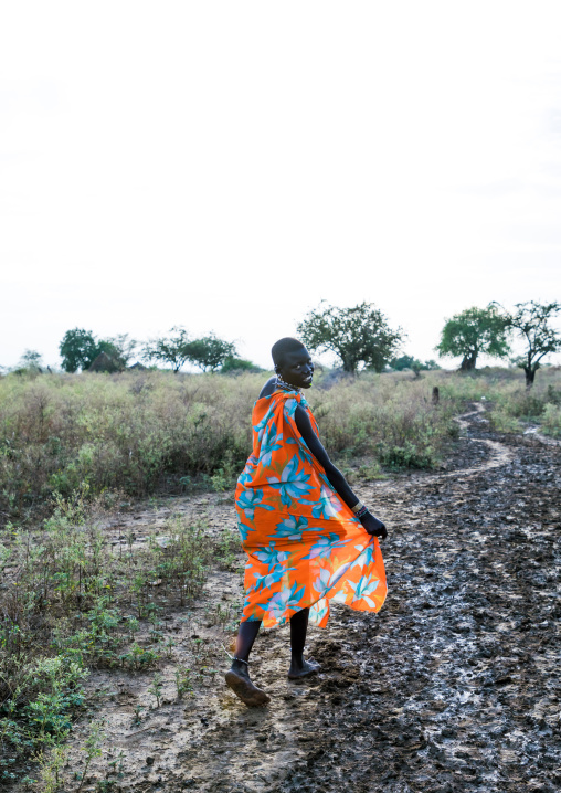 Toposa tribe woman walking on a muddy path, Namorunyang State, Kapoeta, South Sudan